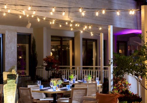 A stylish outdoor restaurant named Sky Beach with string lights, patio tables, and a warm evening vibe.