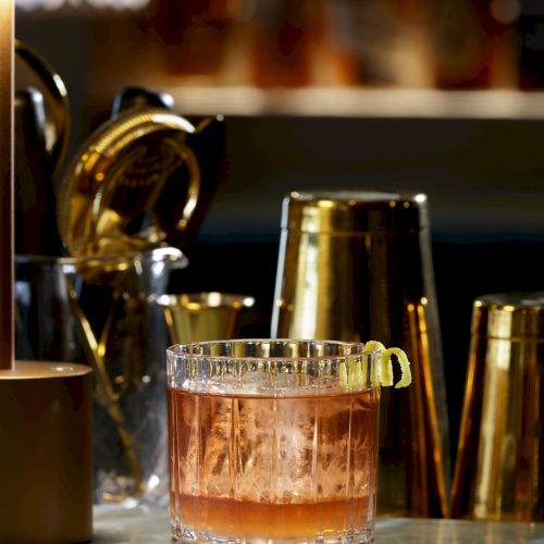 A short, smoky whiskey cocktail on a bar counter, glassy rim and copper-toned lighting in the background, artful and atmospheric.