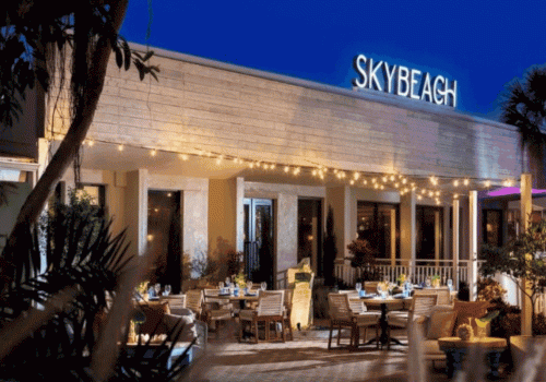 A stylish outdoor restaurant or bar named SkyBeach with string lights and a twilight seating area. Sentence ends with a period.