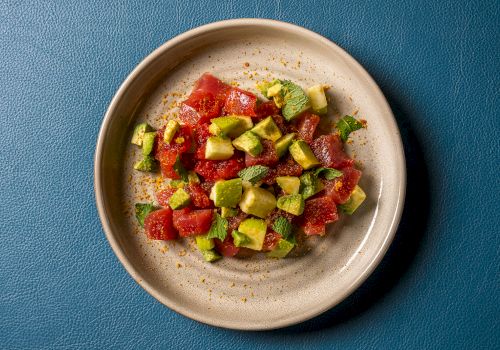 A bowl of watermelon-and-cucumber salad with mint and spice sprinkles on a plate.